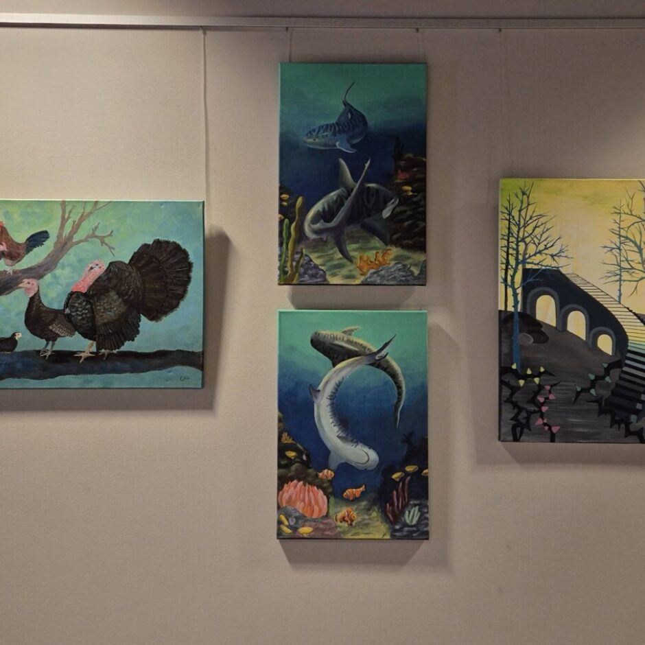 Četras Tukuma Mākslas skolas audzēkņu gleznas izstādē: putni uz zara, zemūdens aina ar zivīm un divas ainavas ar tiltu un kāpnēm parkā.